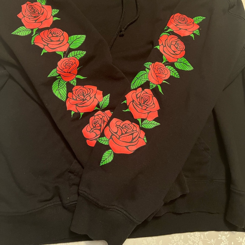 black hoodie with roses on the sleeves and upper left single rose